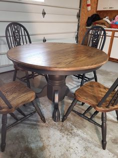 a kitchen table with four chairs and one chair is shown in the foreground, next to a garage door