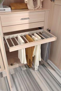 an open drawer in a closet with clothes hanging on the bottom shelf and two folded towels next to it