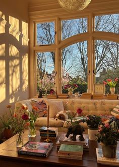 a living room filled with lots of furniture and flowers on top of a coffee table