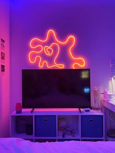 a television sitting on top of a tv stand under a neon lit sign above it