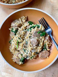 two plates filled with pasta and meat on top of a wooden table next to a fork