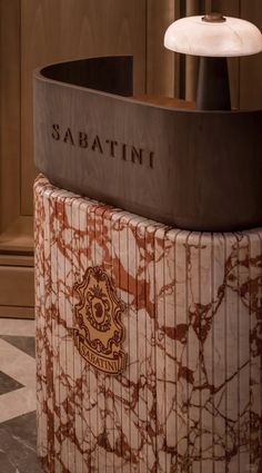 the sabatini sign is on top of a marble pedestal in front of a wall