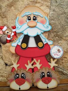 a santa clause with reindeers and a mouse on top of a stone wall next to a plaque