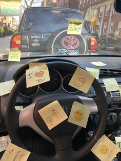 a steering wheel with sticky notes attached to the front and side of it, in front of a car