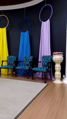 chairs are lined up against the wall in front of colorful drapes and round mirrors