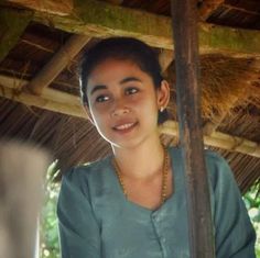 a woman standing under a thatched roof