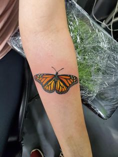 a woman's arm with a butterfly tattoo on the left side of her arm