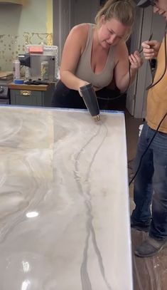 a man and woman are working on a marble counter top