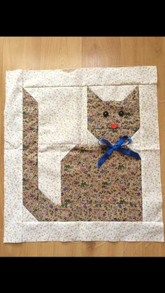 a piece of fabric with a cat on it's back and blue ribbon around its neck