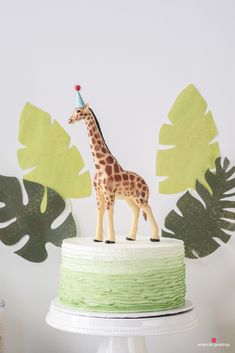 a giraffe figurine is standing on top of a green and white cake