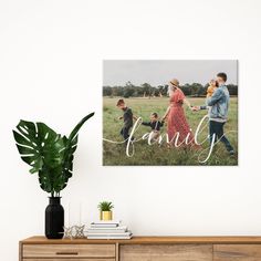 a family photo hanging on the wall next to a potted plant and wooden dresser