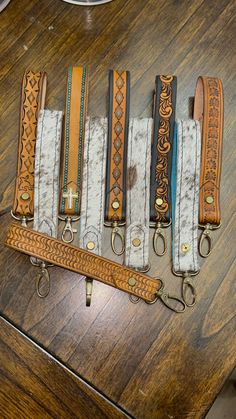 five different types of belts are lined up on a wooden table, with one being used as a keychain
