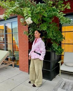 a woman standing in front of a building next to a planter with flowers on it