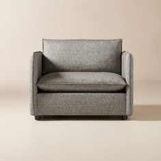 a gray chair sitting on top of a white floor next to a beige wall with a light colored background