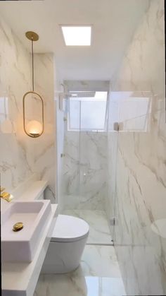 a bathroom with a toilet, sink and shower in white marbled finish on the walls