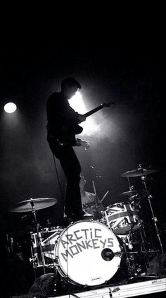 a man standing on top of a drum set in front of a microphone and drumstick