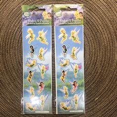 two packages of tinkerbell stickers sitting on top of a carpeted floor