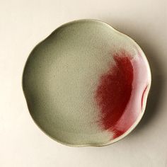 a white and green plate with red paint on it