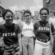 three women standing next to each other in front of a group of people wearing matching shirts