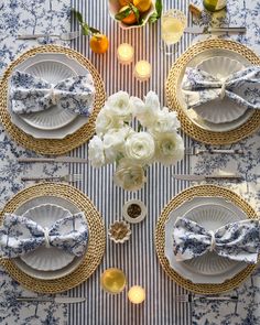 the table is set with blue and white plates, napkins, silverware and flowers