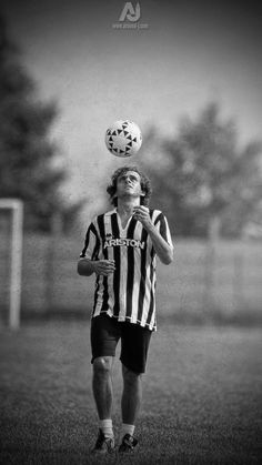 a young man is balancing a soccer ball on his head while standing in the grass