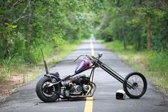 a motorcycle that is sitting on the side of the road with trees in the background