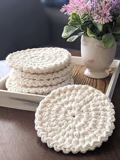 two crocheted coasters sitting on top of a wooden table next to a potted plant