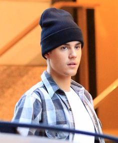 a young man wearing a beanie is walking down the street