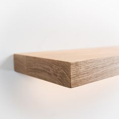 a close up of a wooden shelf against a white wall with light coming from it