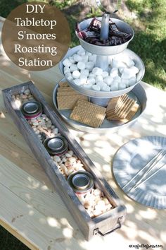 an outdoor table with plates, cups and utensils sitting on top of it