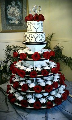 a three tiered wedding cake with red roses on the bottom and white frosting