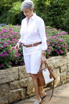 an older woman in white is carrying a brown purse