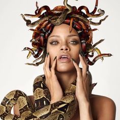 a woman with snakes on her head and hands around her face, holding a snake