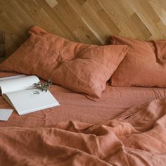 an unmade bed with two pillows and a book on the pillowcase next to it