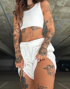 a woman with tattoos on her body and white shorts