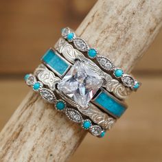 a close up of a ring on top of a wooden stick with turquoise stones and diamonds