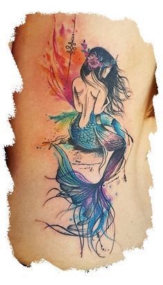 a woman's back tattoo with a mermaid sitting on top of her stomach and colorful feathers