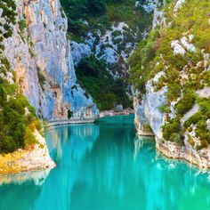 the blue water is surrounded by cliffs and trees