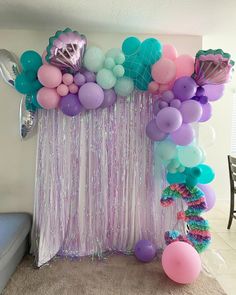 a room with balloons and streamers on the wall, including mermaid tailes in pastel colors