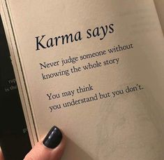 someone is holding an open book with the words karma says on it and there are two fingers