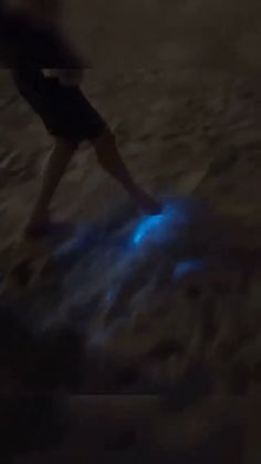 a blurry image of a person walking on the beach at night with blue lights