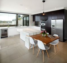 a modern kitchen with an island and dining table in the center, along with large windows