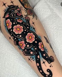 a black cat with pink flowers on it's leg is shown in this tattoo design