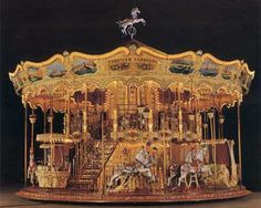 an ornately decorated carousel with horses and riders on it's sides, in front of a dark background