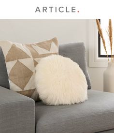 a white pillow sitting on top of a gray couch
