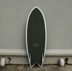 a black and white surfboard leaning up against a wall