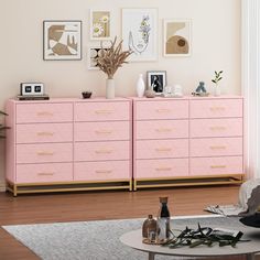 a living room with pink dressers and pictures on the wall above it, in front of a coffee table