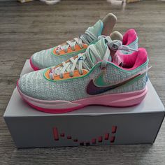 a pair of nike shoes sitting on top of a box with pink and blue accents