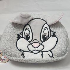 a small gray and white bag with an image of a rabbit on it's face