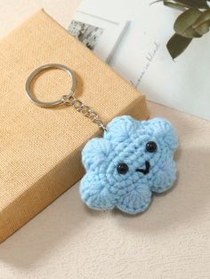 a crocheted keychain with a blue flower on it sitting next to a book